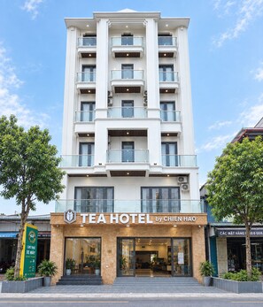Un hotel de varios pisos con una fachada moderna, que cuenta con balcones en cada planta y una entrada a nivel de calle con un letrero que dice 'TEAHOTEL by CHIEN HAO'.