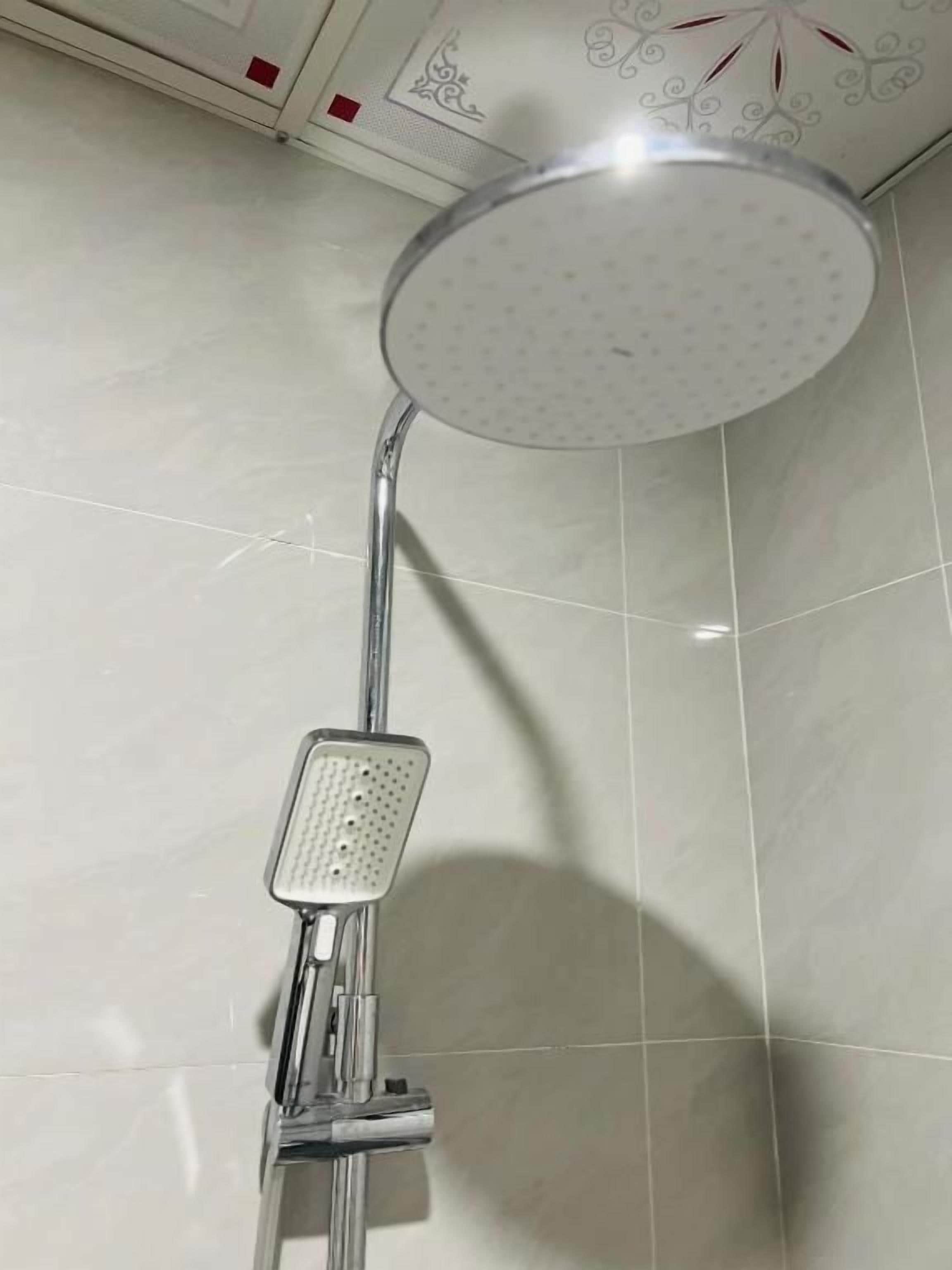 A shower with a roundhead design, chrome fixtures, and a tiled wall.