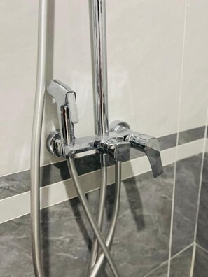 Una ducha con grifería cromada y pared de azulejos.