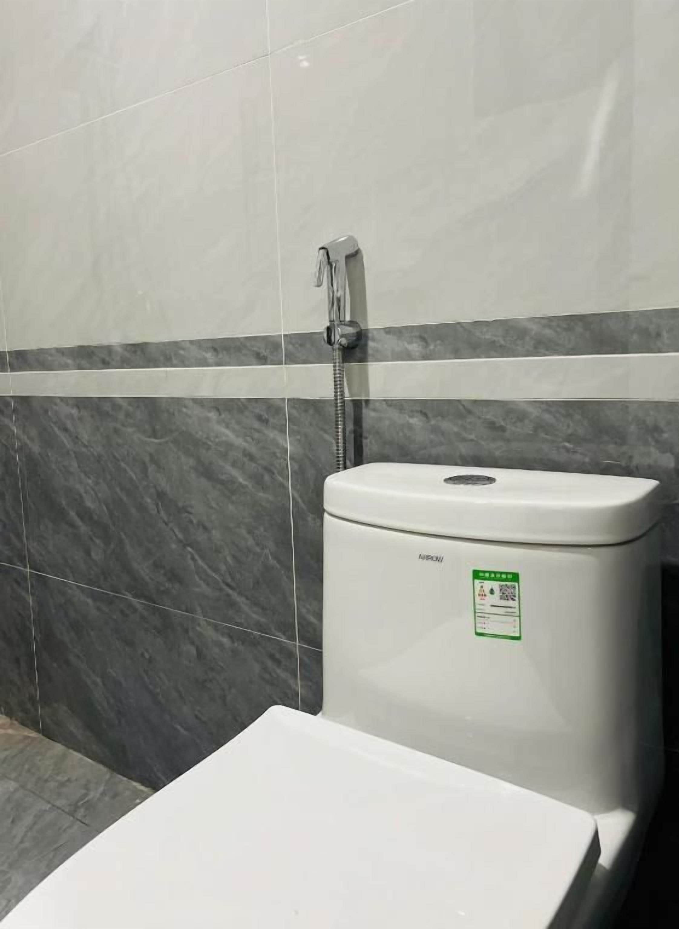 A bathroom with a toilet, a shower, and a tiled wall.