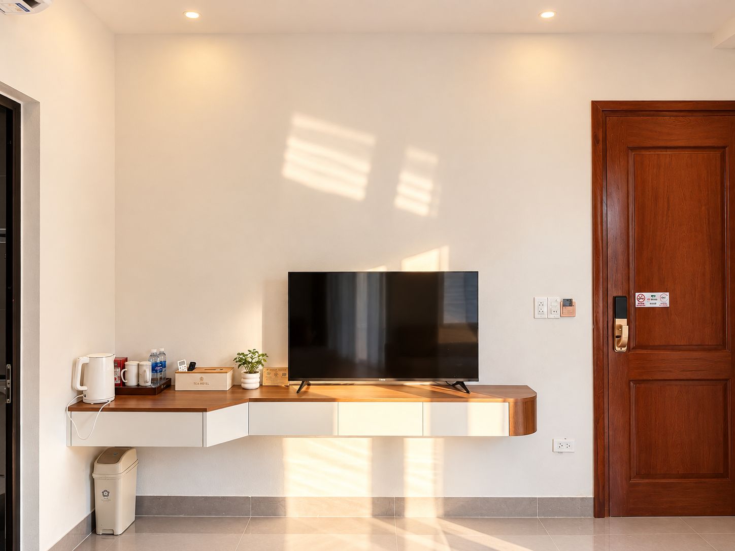 A modern room with a built-in TV, a wooden counter, and a door with a lock.