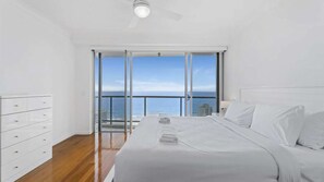 A bedroom with a bed, a dresser, and a view of the sea through a sliding glass door. - Chevron Renaissance Apartment 1323 (Surfers Paradise)