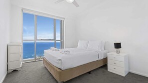 A bedroom with a large window, a bed, a bedside table, and a nightstand. - Chevron Renaissance Apartment 1323 (Surfers Paradise)