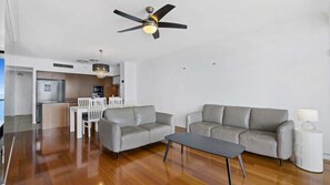 A modern living room with a grey sofa, a coffee table, and a ceiling fan. - Chevron Renaissance Apartment 1323 (Surfers Paradise)