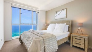 A bedroom with a large window, a bed, a nightstand, and a lamp. - Chevron Renaissance Apartment 1333 (Surfers Paradise)