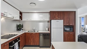 A modern kitchen with white cabinets, a built-in oven, and a dishwasher. - Chevron Renaissance Apartment 2146 (Surfers Paradise)