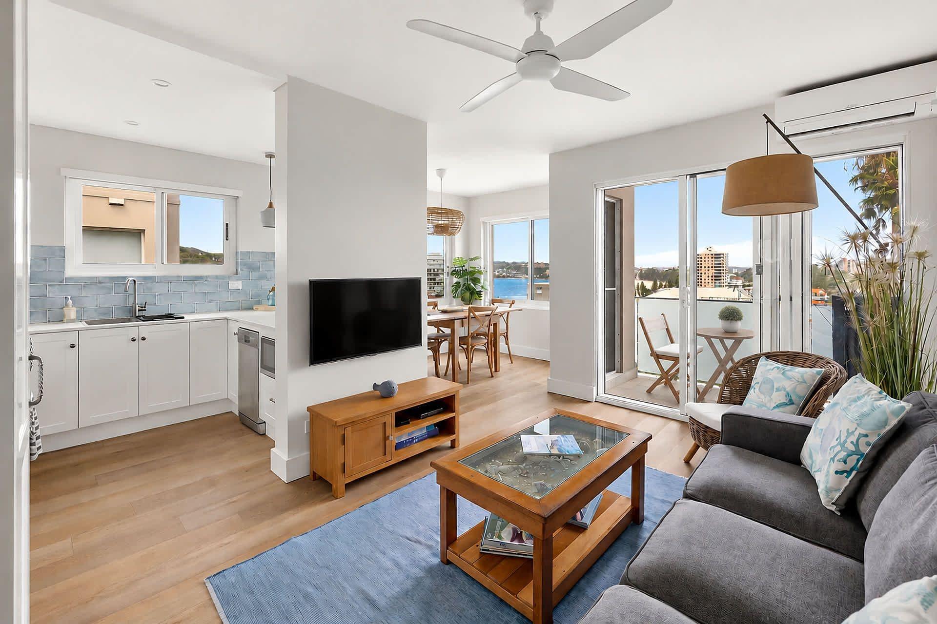 A modern living space with a kitchen, dining area, and a balcony with a view.