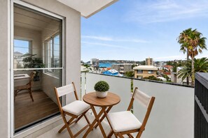 A balcony with two wooden chairs, a small table, and a potted plant. - Beautiful Apartment | Manly Beach Views & Parking (Queenscliff)