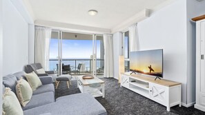 Ein modernes Wohnzimmer mit einer Couch, einem Fernseher und einem Balkon mit Blick auf die Stadt.