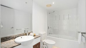 Ein modernes Badezimmer mit einem мраморным Waschbecken, Toilette und einer Duschkabine.