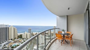 Ein Balkon mit Blick auf das Meer, einen Pool und umliegende Gebäude.