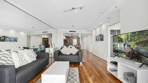 A modern living room with a sofa, coffee table, and a flat-screen TV. - Chevron Renaissance Apartment 2402 (Surfers Paradise)