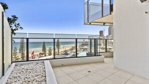 A balcony with a view of the beach and ocean, tiled floor, and a white planter with pebbles. - Esplanade Soul Apartment 402 (Surfers Paradise)