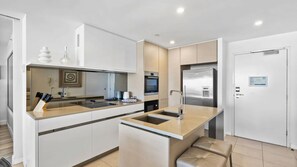 Una cocina moderna con una isla central, horno empotrado y electrodomésticos de acero inoxidable.