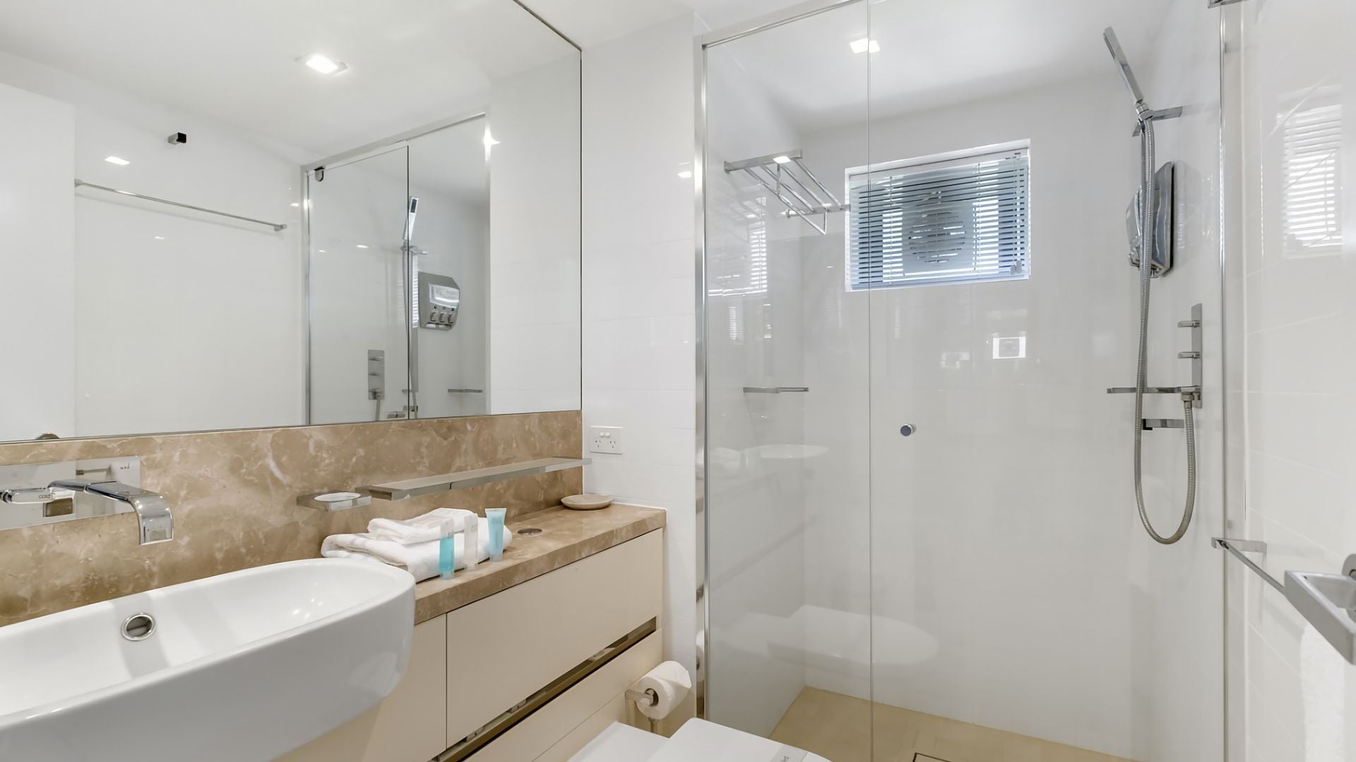 A modern bathroom with a large sink, mirror, and glass shower enclosure.