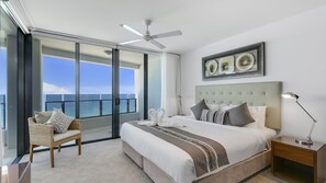 A hotel room with a bed, a chair, a nightstand, a ceiling fan, and a large window with a view of the ocean. - Esplanade Soul Apartment 1605 (Surfers Paradise)