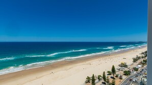 A beach with a clear view of the ocean and a road with buildings and trees. - Esplanade Soul Apartment 1605 (Surfers Paradise)