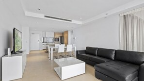 A modern living room with a black leather sofa, a white coffee table, and a flat-screen TV. - Esplanade Soul Apartment 2304 (Surfers Paradise)