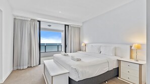 A modern hotel room with a large bed, bedside tables, a bench, and a view of the sea. - Esplanade Soul Apartment 2304 (Surfers Paradise)