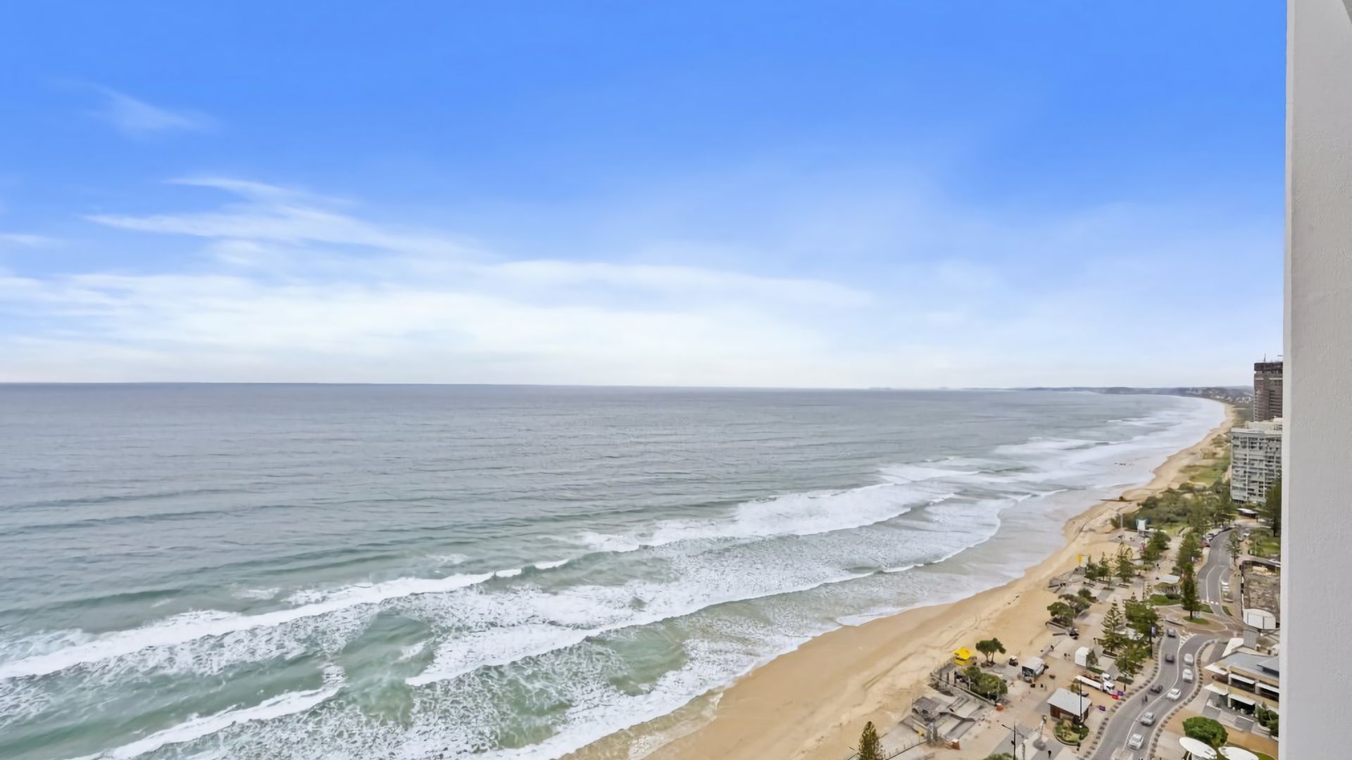 A coastal view with a beach and a road running parallel to the shore.
