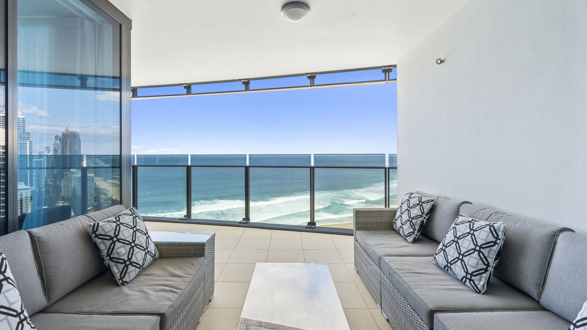 A balcony with a view of the ocean, furnished with two sofas and a coffee table.