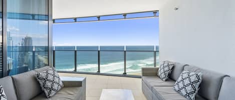 A balcony with a view of the ocean, furnished with two sofas and a coffee table.