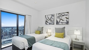 A hotel room with two beds, a city view, abstract wall art, and a bedside table with a lamp. - Esplanade Soul Apartment 3001 (Surfers Paradise)