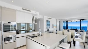 A modern kitchen with a central island, stainless steel appliances, and a view of the ocean. - Esplanade Soul Apartment 3001 (Surfers Paradise)