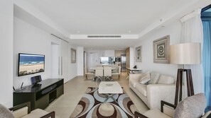 A modern living room with a flat-screen TV, a dining area with a table and chairs, a sofa, and a lamp. - Esplanade Soul Apartment 3004 (Surfers Paradise)