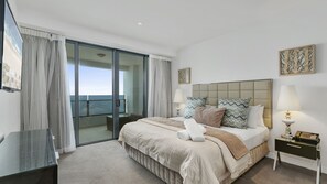 A hotel room with a bed, bedside tables, a glass partition, and a view of the sea. - Esplanade Soul Apartment 3004 (Surfers Paradise)