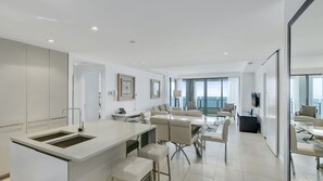A modern hotel room with a kitchen area, dining space, and a balcony with a view. - Esplanade Soul Apartment 3004 (Surfers Paradise)