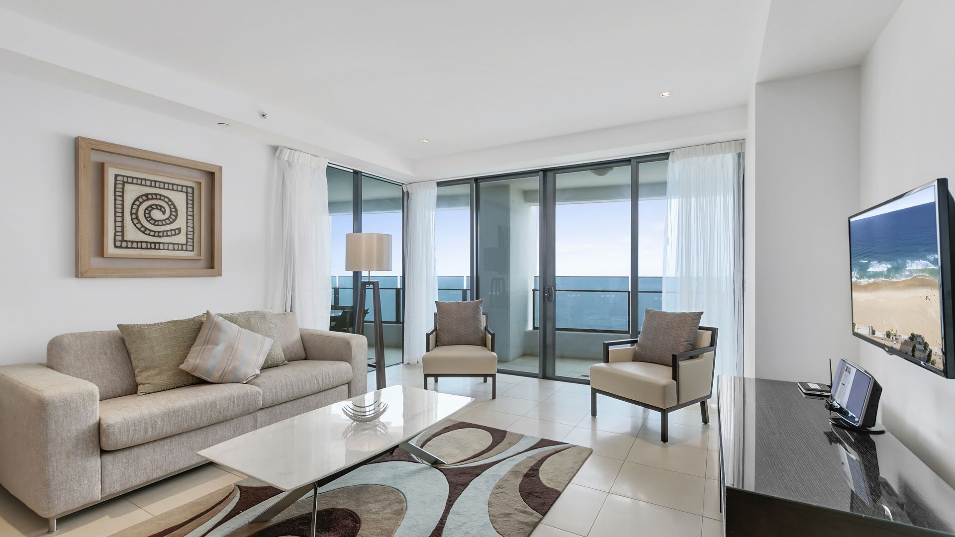 A modern living room with a sofa, chairs, a coffee table, and a TV.