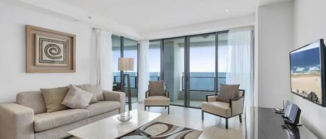 A modern living room with a sofa, chairs, a coffee table, and a TV.