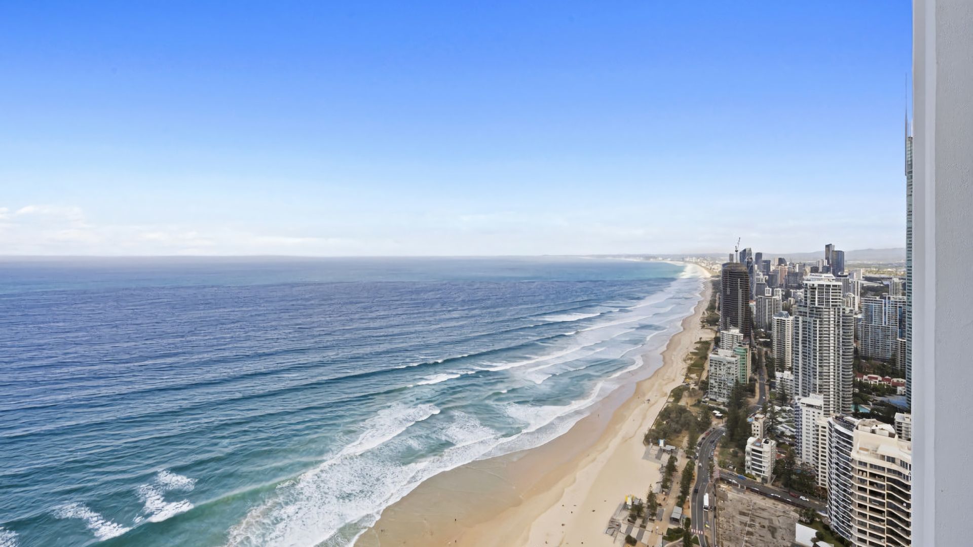 A coastal cityscape with a beach and high-rise buildings.