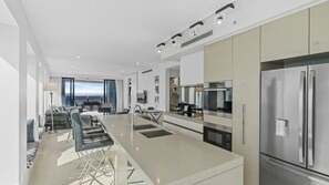 A modern kitchen with a central island, stainless steel appliances, and a view to the outside. - Esplanade Soul Apartment 5005 (Surfers Paradise)
