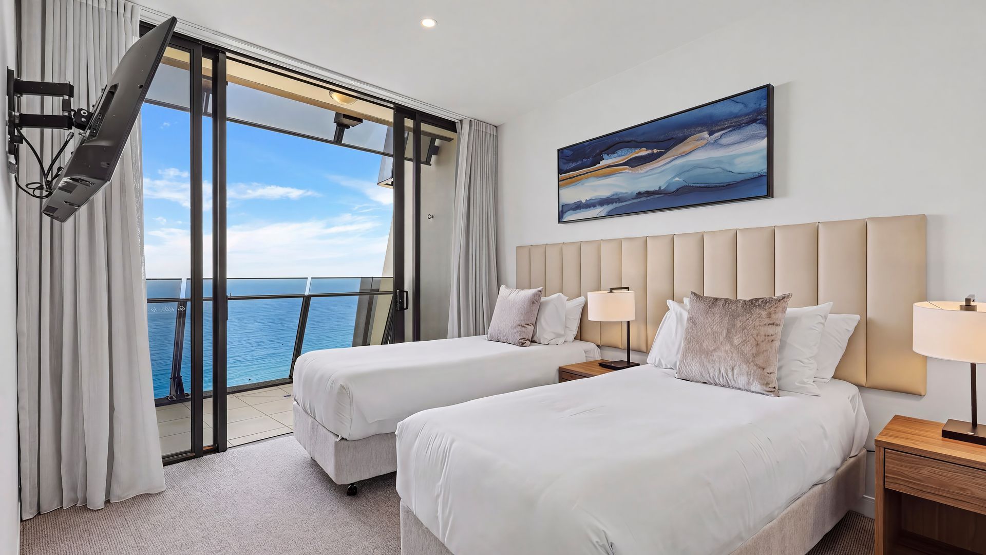A hotel room with two beds, a large window with a view of the sea, and a painting on the wall.