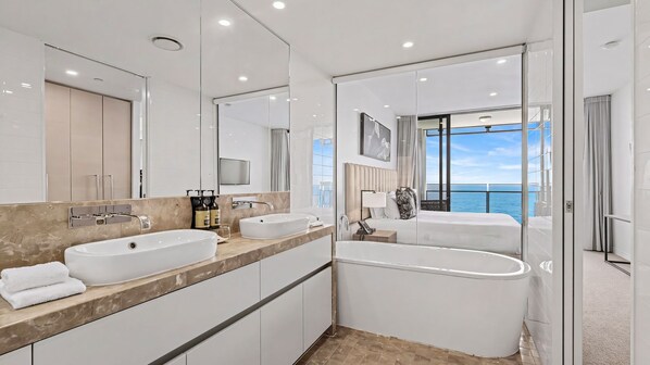 Une salle de bain moderne avec une grande baignoire, deux lavabos et un grand miroir.