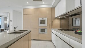 A modern kitchen with built-in appliances, a stainless steel sink, and a large window. - Esplanade Soul Apartment 6102 (Surfers Paradise)
