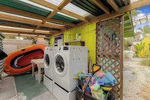 Uma área de lavanderia com máquina de lavar, varal e boia de piscina.