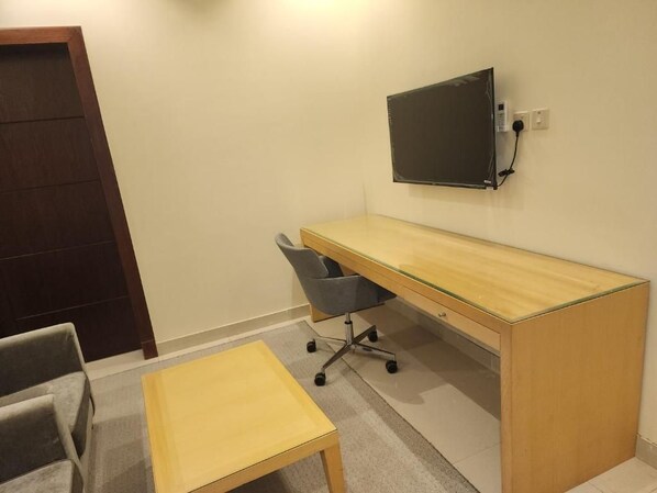 A small office space with a desk, chair, and a television mounted on the wall.