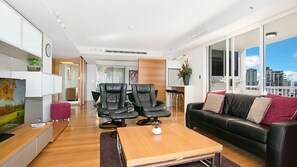 Ein modernes Wohnzimmer mit einer Couch, zwei Ledersesseln, einem Couchtisch und einem Fernseher.