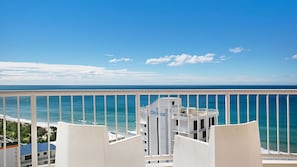 Un balcón con vista al océano y un edificio con la señalización 'Olympus'.