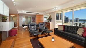 Una sala de estar moderna con un sofá de cuero negro, una mesa de centro de madera y dos sillones de cuero negro.
