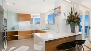 A modern kitchen with a white countertop, wooden cabinets, and a large window. - Moroccan Apartment 269 (Surfers Paradise)