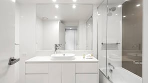 A modern bathroom with a large mirror, a round sink, and a glass-enclosed shower area. - Orchid Residences Apartment 10704 (Surfers Paradise)