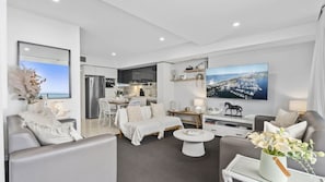 Ein modernes Wohnzimmer mit einer Couch, einem Couchtisch und einem Fernseher.