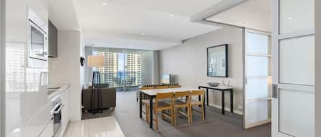 A modern kitchen with a dining area, large windows, and a view of high-rise buildings.
