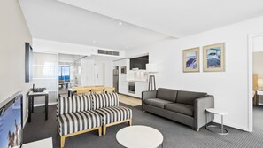 Ein modernes Wohnzimmer mit einem grauen Sofa, einem gestreiften Ottomanen und einem runden Couchtisch.