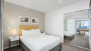 Ein Hotelzimmer mit einem Bett, einem Nachttisch, einer Lampe, einem Spiegel und Blick auf den Balkon.
