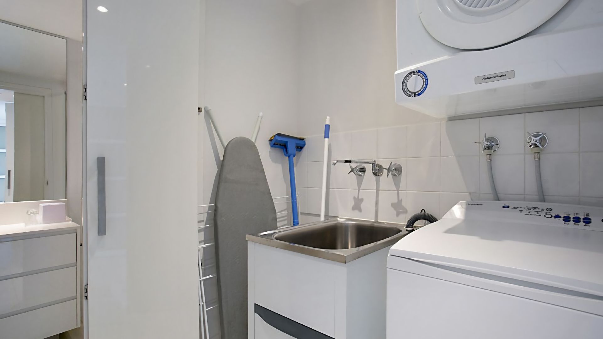 A modern bathroom with a built-in washing machine, a sink, and a shower area.